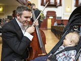 Cellist Richard Belcher played “Twinkle Twinkle Little Star” for his 14-month-old son Finn before performing in Saturday’s concert at City Hall 