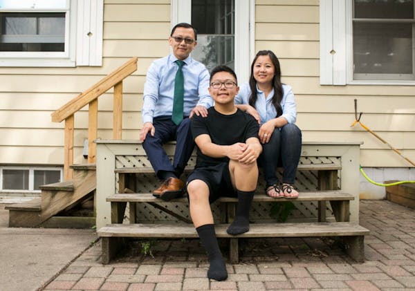 Dmitri Moua, center, and his parents at their home in Minnesota. Dmitri loves to dance but can't dance competitvely with his team and has to sit on th