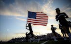 Buffalo defensive lineman Tucker Johnson (15) ran the US flag onto the field before the start of Friday night's game against Elk River. ] AARON LAVINS
