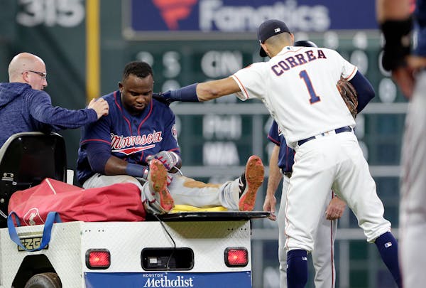 Twins designated hitter Miguel Sano gets a pat on the back from Houston Astros shortstop Carlos Correa as he is taken off the field after an injury on