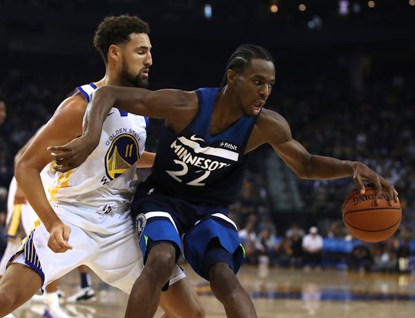 The Timberwolves' Andrew Wiggins, right, keeps the ball from Golden State Warriors' Klay Thompson