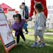 Sisters Rory, 2, left, and Henri, 3, look at a child's art work on a promotional billboard while visiting the Farmers Market with their grandmother Ju