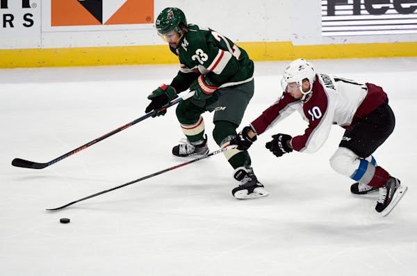 Colorado Avalanche's Sven Andrighetto (10), of Switzerland, takes the puck from Minnesota Wild's J.T. Brown (23) during the first period of an NHL hoc