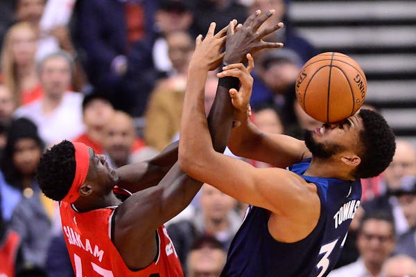 Raptors forward Pascal Siakam and Timberwolves forward Karl-Anthony Towns try to control a loose ball during first half