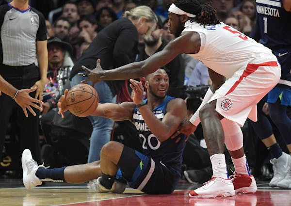 Timberwolves guard Josh Okogie tried to pass while seated on the floor and under pressure from Clippers forward Montrezl Harrell during the first half