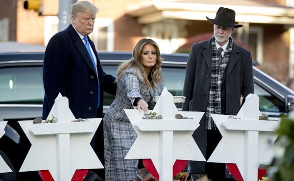 First lady Melania Trump, accompanied by President Donald Trump, and Tree of Life Rabbi Jeffrey Myers, right, puts down a white flower at a memorial f