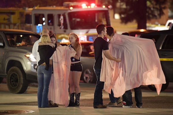 People comfort each other as they stand near the scene Thursday, Nov. 8, 2018, in Thousand Oaks, Calif. where a gunman opened fire Wednesday inside a 