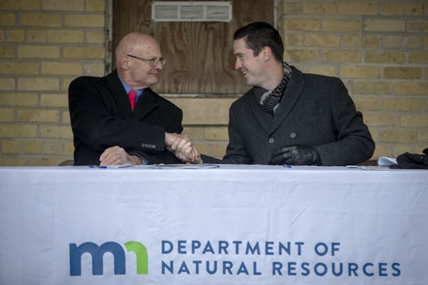 DNR Commissioner Tom Landwehr, and Dominium's Owen Metz shook hands after signing an agreement with Dominium, an affordable housing development and ma