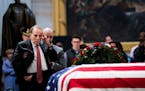Former Sen. Bob Dole (R-Kansas) is helped to stand as he salutes the coffin bearing the remains of former President George H. W. Bush at the Capitol i