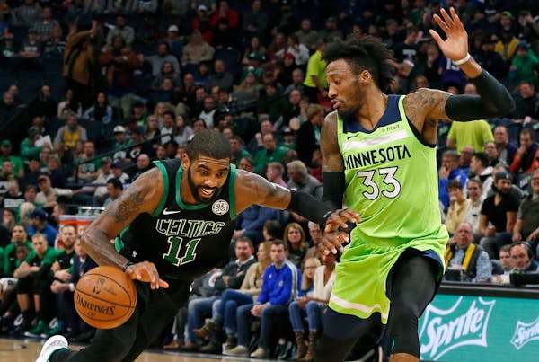 The Celtics' Kyrie Irving, left, drives around the Timberwolves Robert Covington during the first half Saturday.