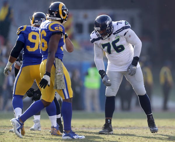 Seattle Seahawks offensive tackle Duane Brown, right, lines up against Los Angeles Rams defensive end Aaron Donald, left, and defensive end Dante Fowl