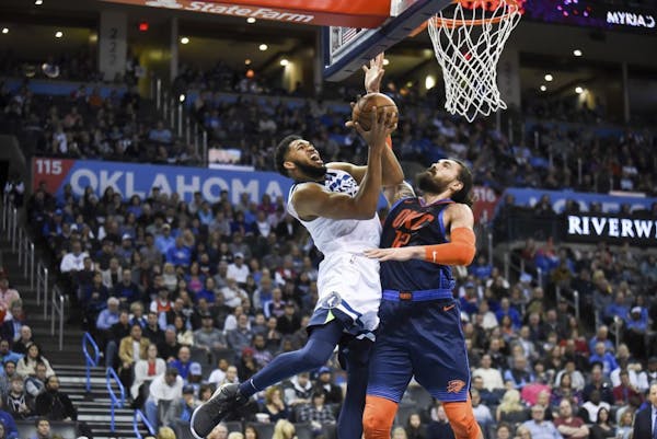Minnesota Timberwolves center Karl-Anthony Towns, left, goes up to shoot over Oklahoma City Thunder center Steven Adams, right, in the first half of a