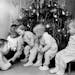 1957: Big brother Mark Meester, 8, reads a Christmas Eve bedtime story to his younger brothers and sisters. They are (from left) Eric, 6, and triplets