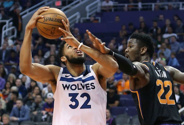 Timberwolves center Karl-Anthony Towns drives to the basket as Suns center Deandre Ayton defends during the first half