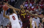 Minnesota's Dupree McBrayer (1) reaches for the ball held by Wisconsin's D'Mitrik Trice (0) during the first half of an NCAA college basketball game T