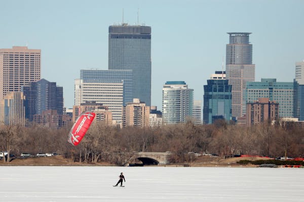 Kite boarders skim across Bde Maka Ska in front of the Minneapolis skyline in March.