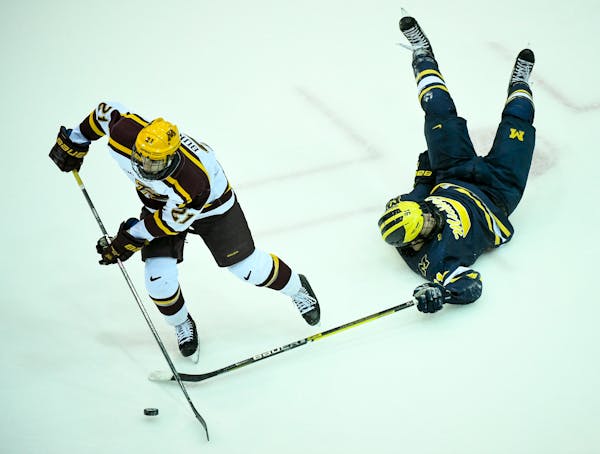 Michigan forward Nick Pastujov was upended as he was challenged by Gophers forward Nathan Burke during Friday night's loss. The Gophers won on Saturda