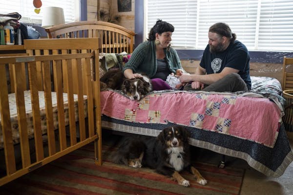 In this Dec. 5, 2018 photo, new parents Erin Petz and Matt Tyler sit with their newborn Corwyn and their two dogs in Grand Marais, Minn. The hospital 