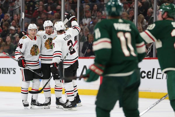 Erik Gustafsson, middle celebrates with teammates Dominik Kahun, left and Duncan Keith after Gustafsson scored a goal against the Wild during the seco