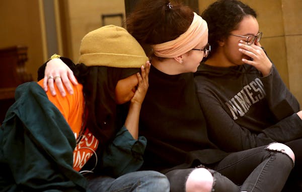 From left, Muna Galbayte Anna Feist and Maya West, all of Eden Prairie, comforted one anotehr as names of Minnesota gun victims from 2018 were read al