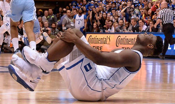 Duke forward Zion Williamson holds his knee after injuring himself and damaging his shoe during the opening moments of the game in the first half on W