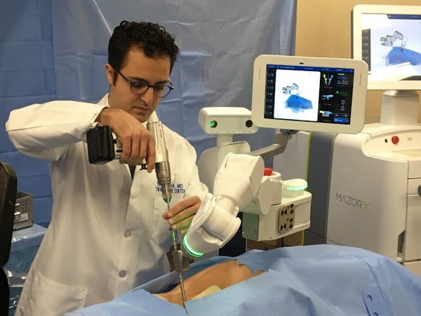 Dr. Eiman Shafa of the Twin Cities Spine Center, left, demonstrated the use of Medtronic’s Mazor X robotically navigated spine-surgery system Tuesda