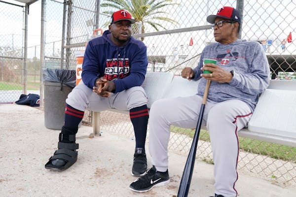 Minnesota Twins third baseman Miguel Sano (22) talked with Twins hall of famer Rod Carew (29) in the dugout at the practice field as he sat out anothe