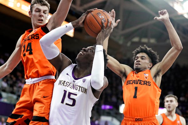 Washington forward Noah Dickerson (15) tries to get a shot off as Oregon State's Kylor Kelley, left, and Stephen Thompson Jr., right, defend