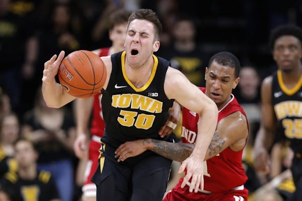 Iowa guard Connor McCaffery is fouled by Indiana guard Devonte Green, right, during the second half of an NCAA college basketball game Friday, Feb. 22