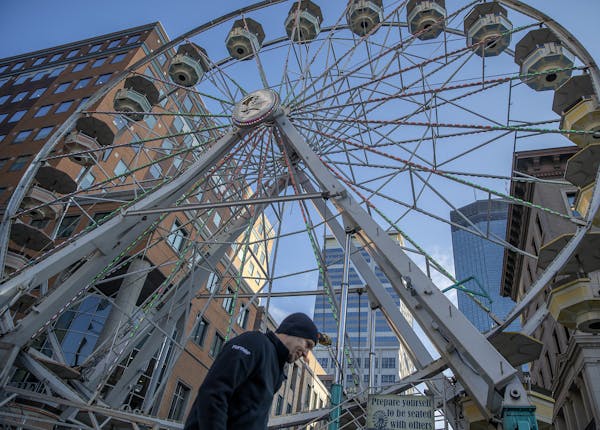 Tim Leininger placed signs Wednesday near the giant Ferris wheel in downtown Minneapolis ahead of Final Four festivities.