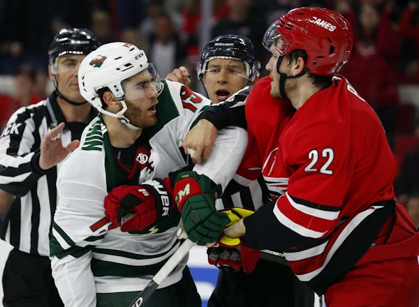 Luke Kunin (19) of the Wild roughed it up with Brett Pesce of the Hurricanes in Carolina’s 5-1 win on Saturday night in Raleigh.