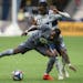 Vancouver Whitecaps’ Alhassane Bangoura, rear, plays the ball against Minnesota United’s Romain Metanire in the second half of the March 2 match i