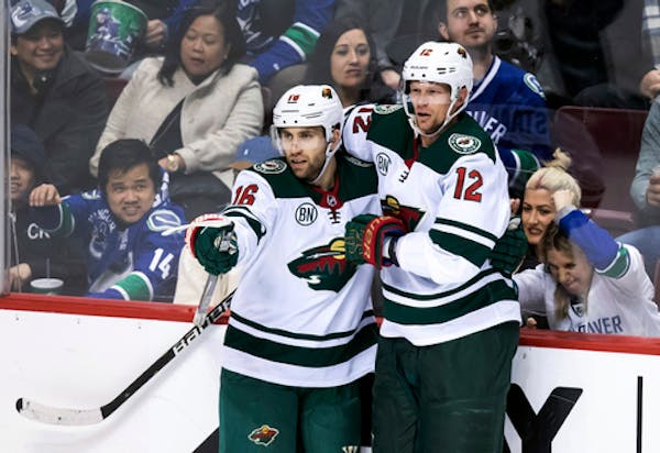 Minnesota Wild's Jason Zucker, left, and Eric Staal celebrate Zucker's second goal against the Vancouver Canucks during the second period of an NHL ho