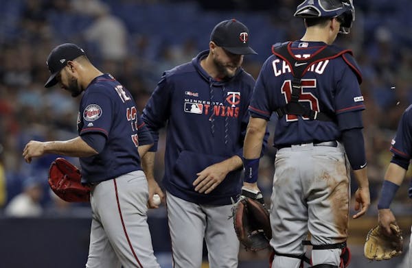 Minnesota Twins manager Rocco Baldelli, center, takes starting pitcher Martin Perez, left out of the baseball game against the Tampa Bay Rays during t