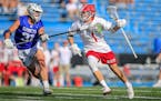 Jack VanOverbeke (1) drives against St. Thomas Academy’s Ben Mansur (31) in the first half of a boys lacrosse state tournament semifinal at Minneton