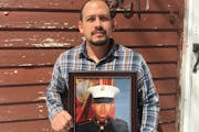 In this April 13, 2019, photo provided by the ACLU of Minnesota, Mark Esqueda poses for a portrait with a photo of him as a U.S. Marine, in Heron Lake