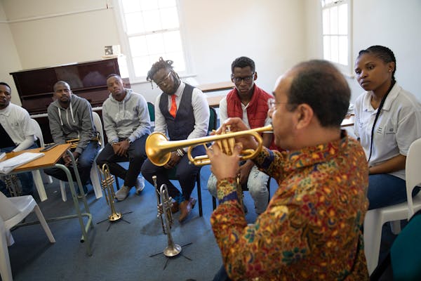 Trumpet players from the KwaZulu Natal Youth Wind Band listen as Manny Laureano from the Minnesota Orchestra demonstrates technique. ] LEILA NAVIDI �