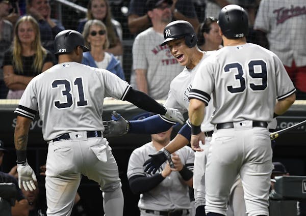 Aaron Judge, center, congratulates teammate Aaron Hicks after Hicks hit a two-run home run when the Twins were one out from winning on Tuesday.