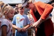 Sen. Elizabeth Warren (D-Mass.), a Democratic presidential hopeful, signs her autograph for young fairgoers at the Iowa State Fair in Des Moines, Iowa