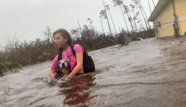 Julia Aylen wades through waist deep water carrying her pet dog as she is rescued from her flooded home during Hurricane Dorian in Freeport, Bahamas, 