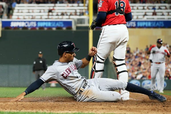 Cleveland's Oscar Mercado slides safely into home to score on a sacrifice fly by Yasiel Puig against the Twins to tie the score during the eighth inni