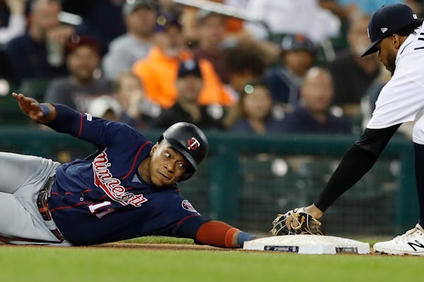 The Twins' Jorge Polanco reaches back to safely to touch third as Tigers third baseman Dawel Lugo attempts the tag during the fourth inning
