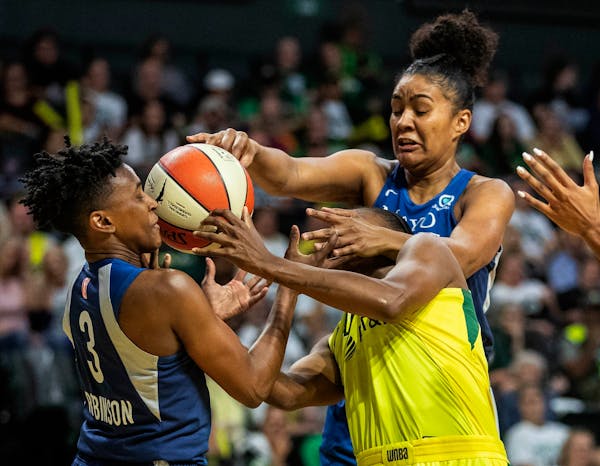 Seattle's Jewell Loyd, lower right, fends off two Lynx players to get off a shot during the first half of Wednesday's WNBA Western Conference playoff 