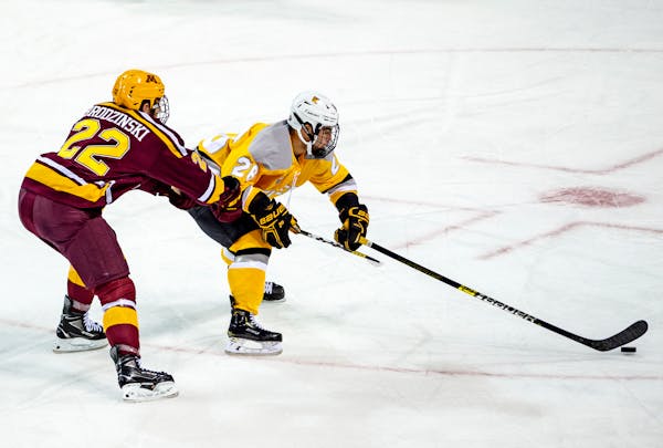 Colorado College defenseman Brady Smith, right, fights to maintain control of the puck as Gophers forward Bryce Brodzinski defends during the first pe