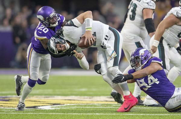 Eric Kendricks, right, and Mackensie Alexander combined to sack Eagles quarterback Carson Wentz on Sunday.