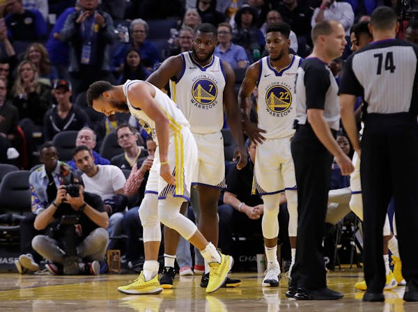 Golden State Warriors' Stephen Curry, left, grimaces after Phoenix Suns' Aron Baynes fell onto him during the second half.