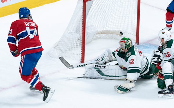 Montreal Canadiens' Nick Suzuki, left, scores past Wild goaltender Alex Stalock during first-period action.