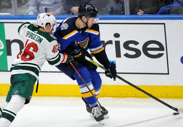 The Wild's Jared Spurgeon reaches for the puck with St. Louis Blues' Zach Sanford during the second period