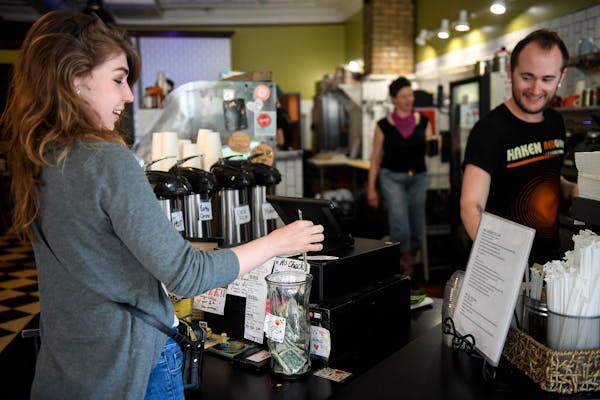 Barista Andy Regan, right, watched as Jennifer Ivers, of Minneapolis, placed a dollar in the tip jar Wednesday afternoon at Maeve’s Cafe. ] AARON LA