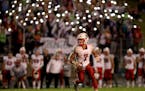 Under the lights from mobile phones in the student section, Lakeville North High quarterback RaJa Nelson (7) rolled out near the end of the game again